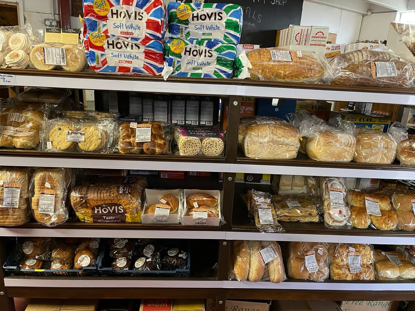 Bakery shelves stacked with bread, buns and crumpets